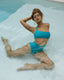 Woman in an aqua blue high waisted bikini set sitting in a swimming pool